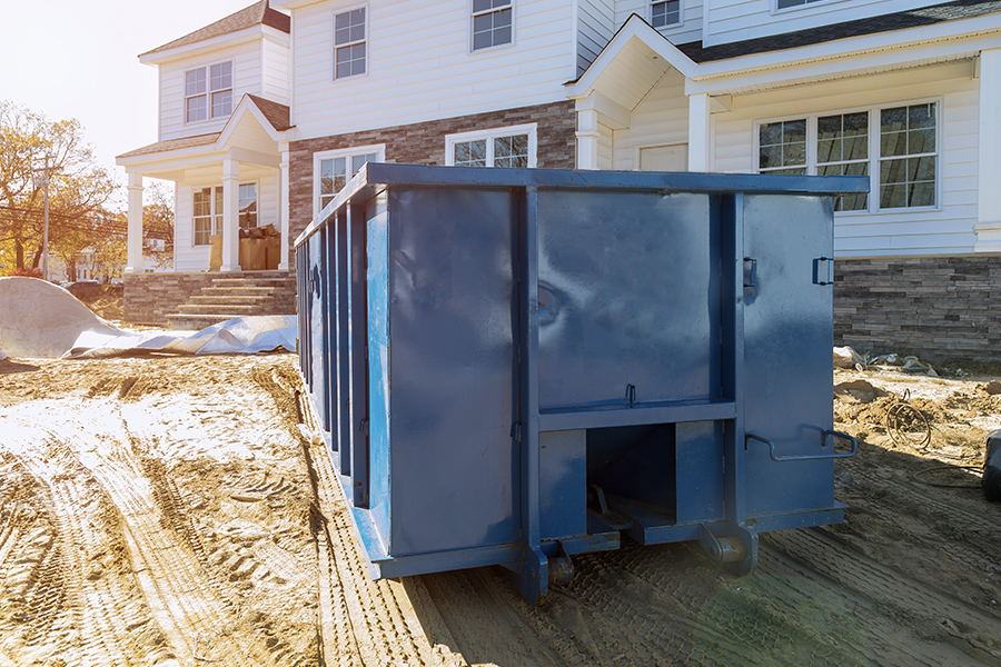 Roll-Off Contractor Insurance - Blue Dumpster in Front of New Home for Waste and Construction Materials at Construction Site